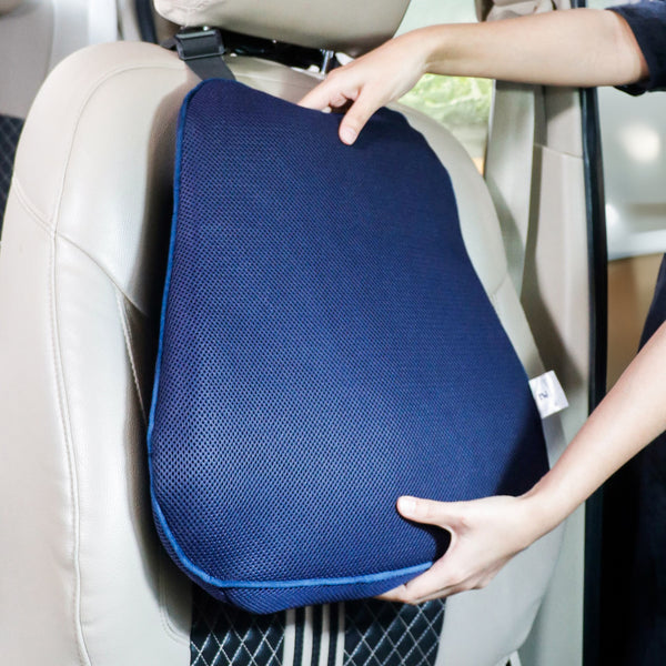 Car seat with an attached blue lumbar support cushion, being adjusted by a person for better back comfort.
