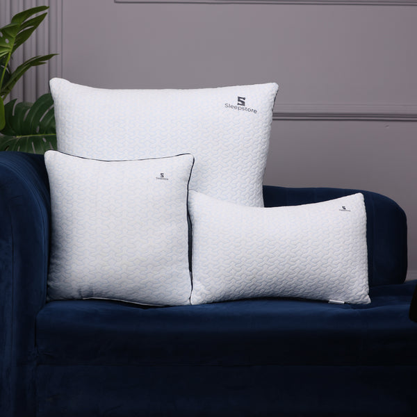Three white Sleepstore pillows of different sizes placed on a dark blue sofa for display.