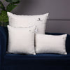 Set of three white Sleepstore pillows in different sizes placed on a dark blue sofa