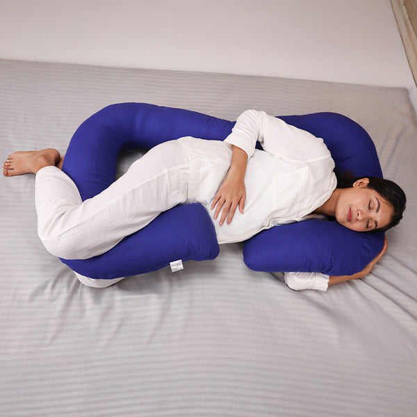 Pregnant woman sleeping comfortably with a U-shaped body pillow in bed.