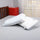 Reversible memory foam pillow with adjustable layers placed on a bed for display.