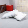 Reversible memory foam pillow with adjustable layers placed on a bed for display.