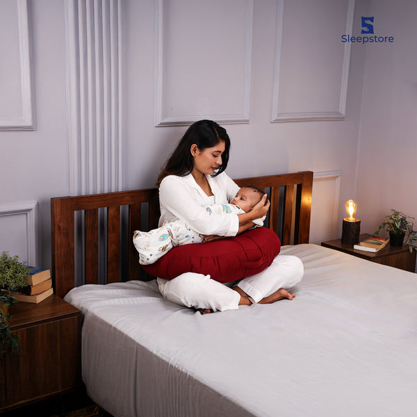 Mother nursing baby using red Sleepstore Feeder Pillow for comfortable breastfeeding support