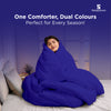 Woman wrapped in a cozy dual-color comforter, smiling peacefully on bed.
