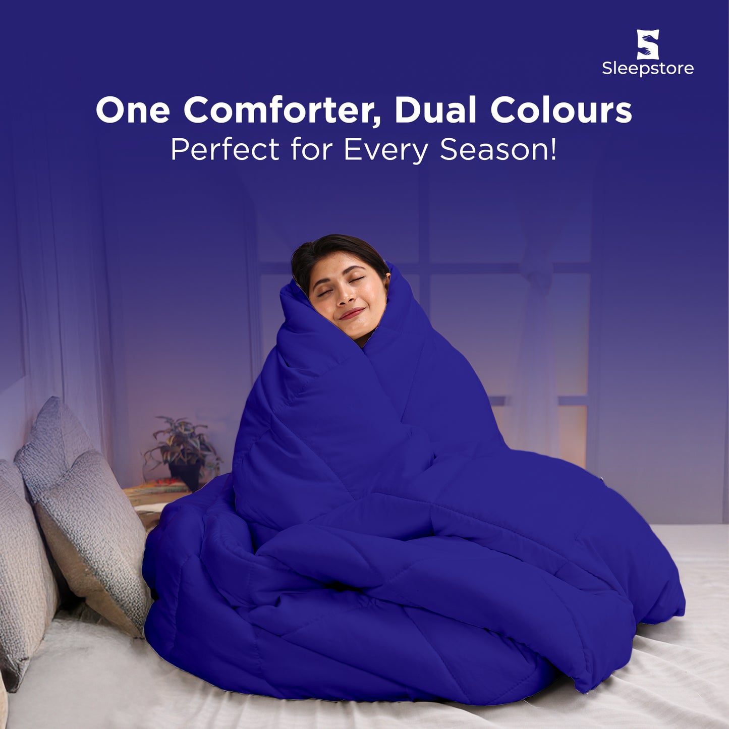 Woman wrapped in a cozy dual-color comforter, smiling peacefully on bed.