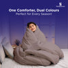 Woman wrapped in a beige dual-color comforter, sitting cozy and smiling on bed.