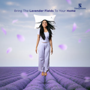 Woman in lavender field smiling with Sleepstore pillow behind head and petals falling.