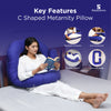 Woman reading a book while using a blue C-shaped maternity pillow on bed.