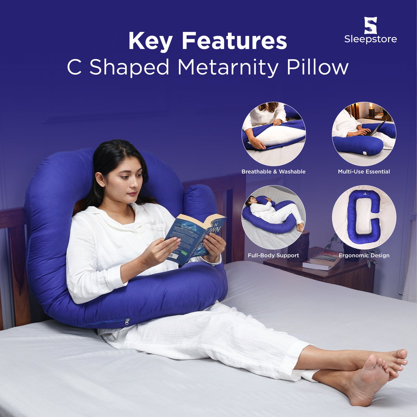 Woman reading a book while using a blue C-shaped maternity pillow on bed.