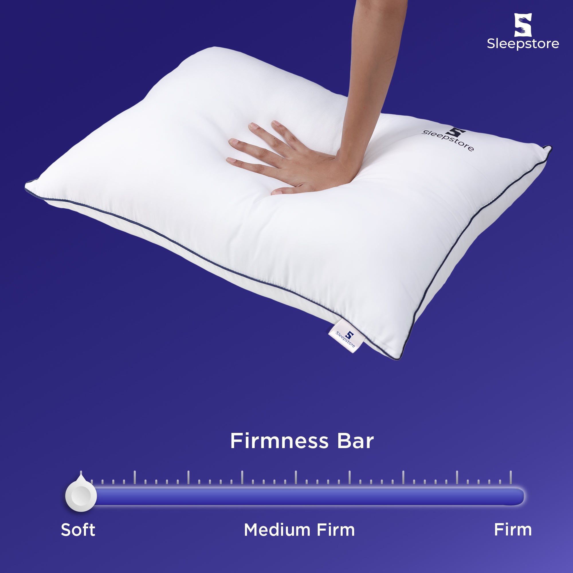 Hand pressing soft white Sleepstore pillow with firmness bar showing ultra-soft comfort level.